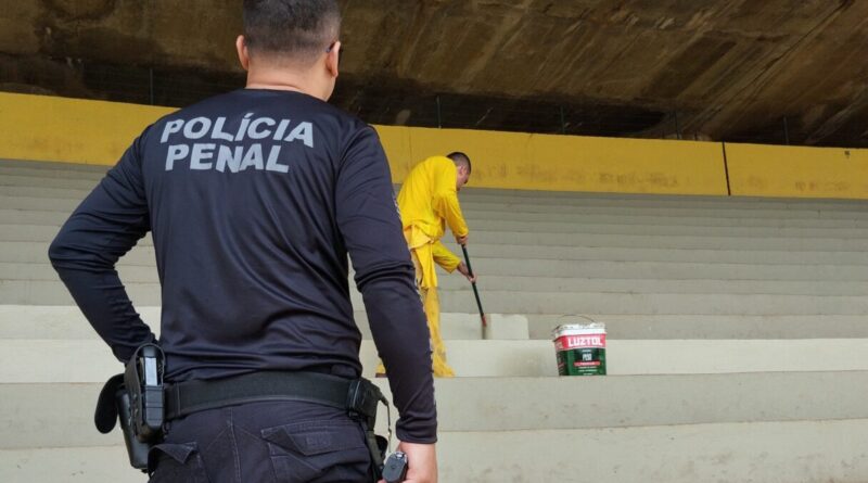 Reeducandos trabalham na pintura da arquibancada do Serra Dourada, em Goiânia, sob vigilância policial (Foto: DGPP)