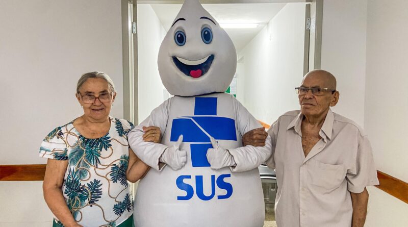 Casal de idosos aproveitou Dia D para se vacinar contra gripe, na presença do Zé Gotinha